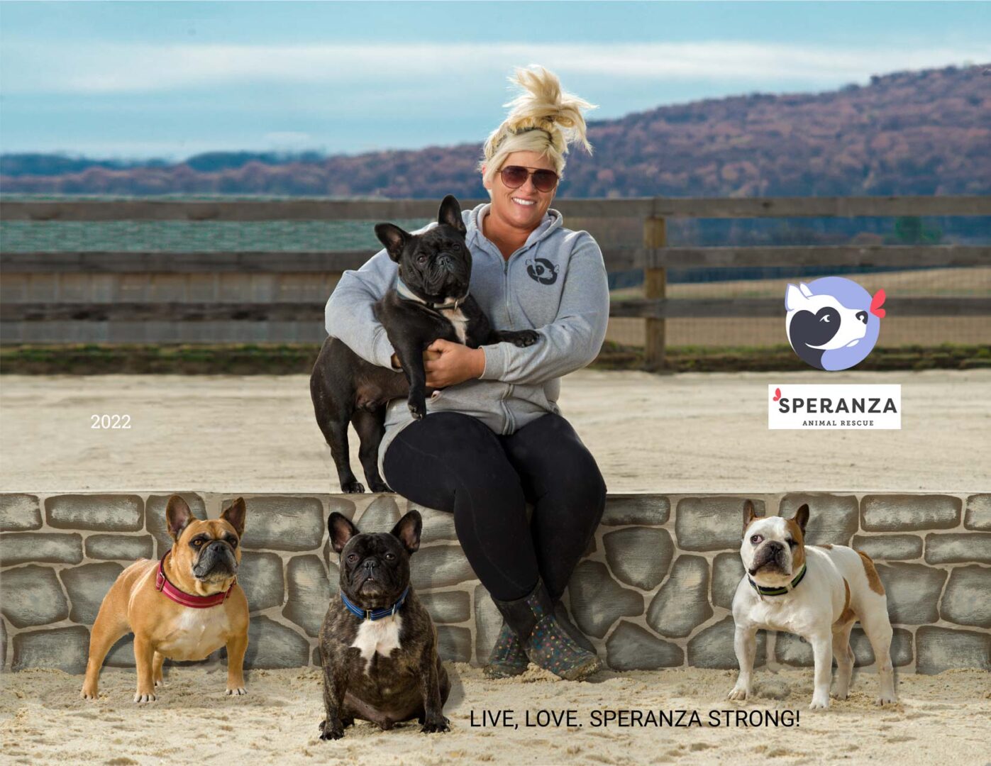 A woman holding two dogs in front of four other dogs.