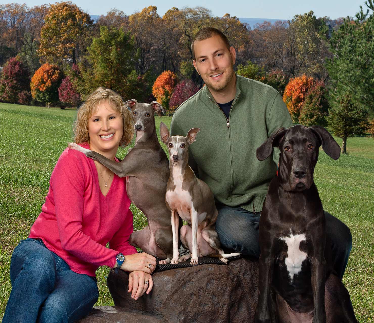 A man and woman posing with two dogs.
