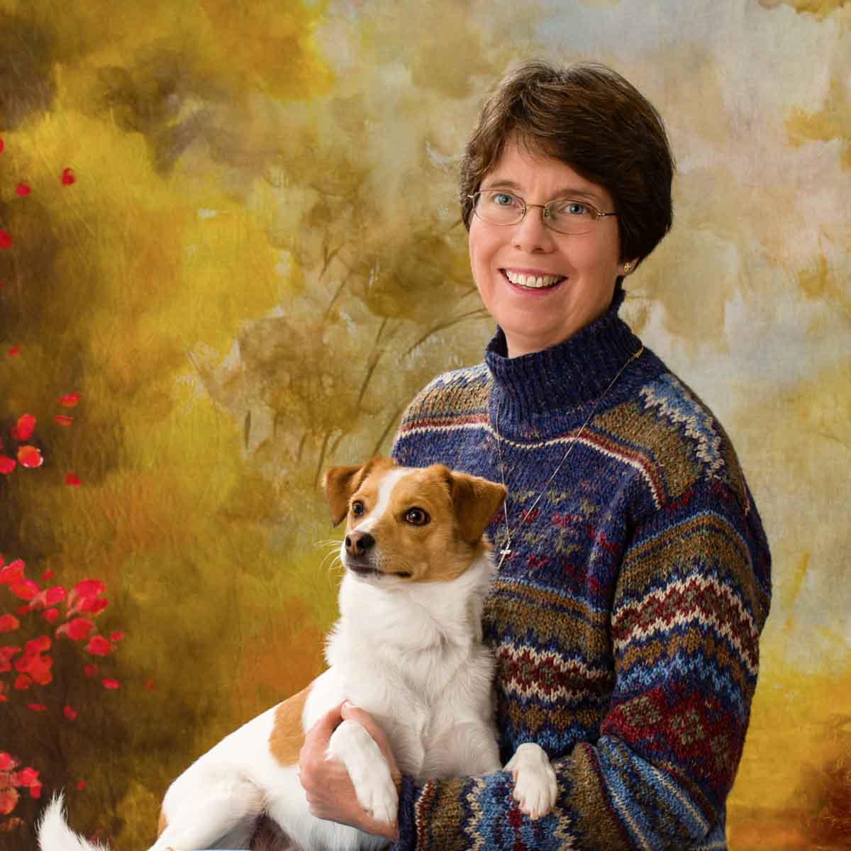 A woman holding her dog in front of a painting.