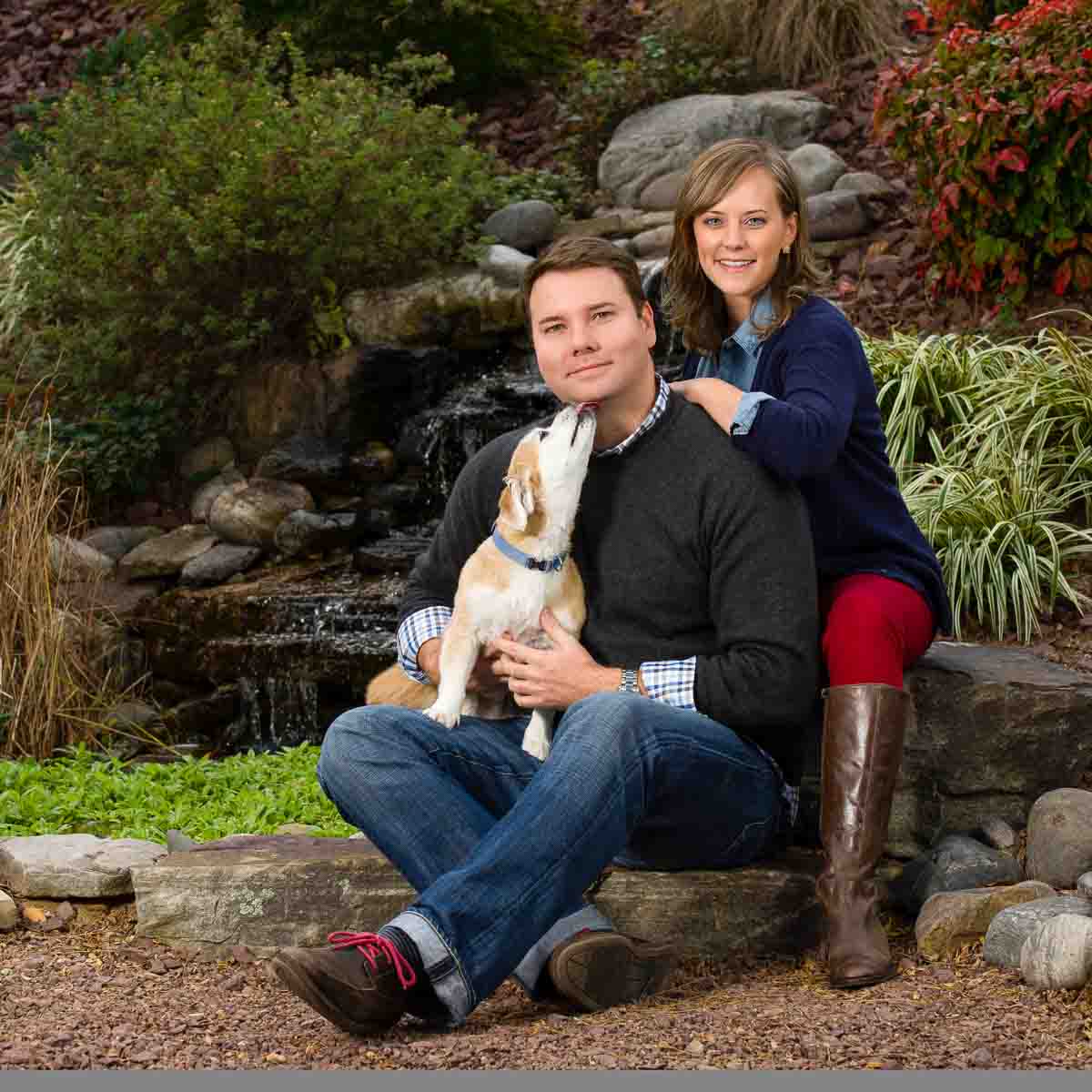 A man and woman sitting on the ground with their dog.