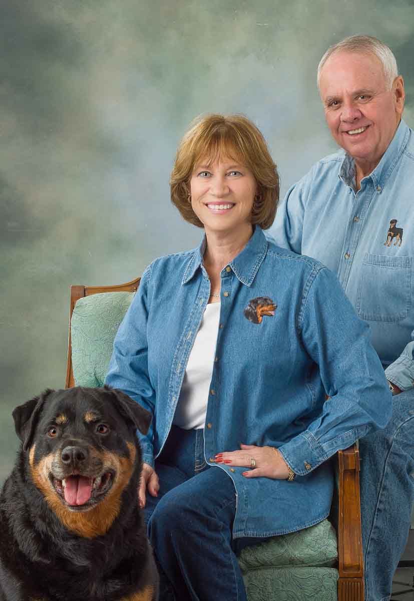 A man and woman sitting in front of a dog.