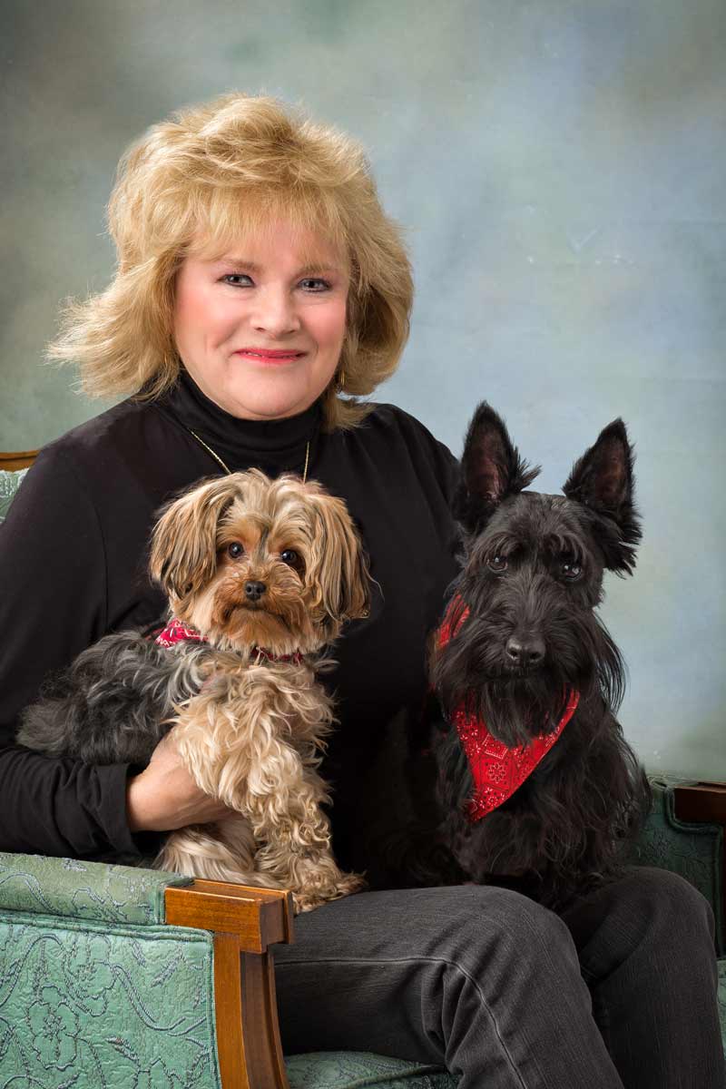 A woman sitting with two dogs on her lap.