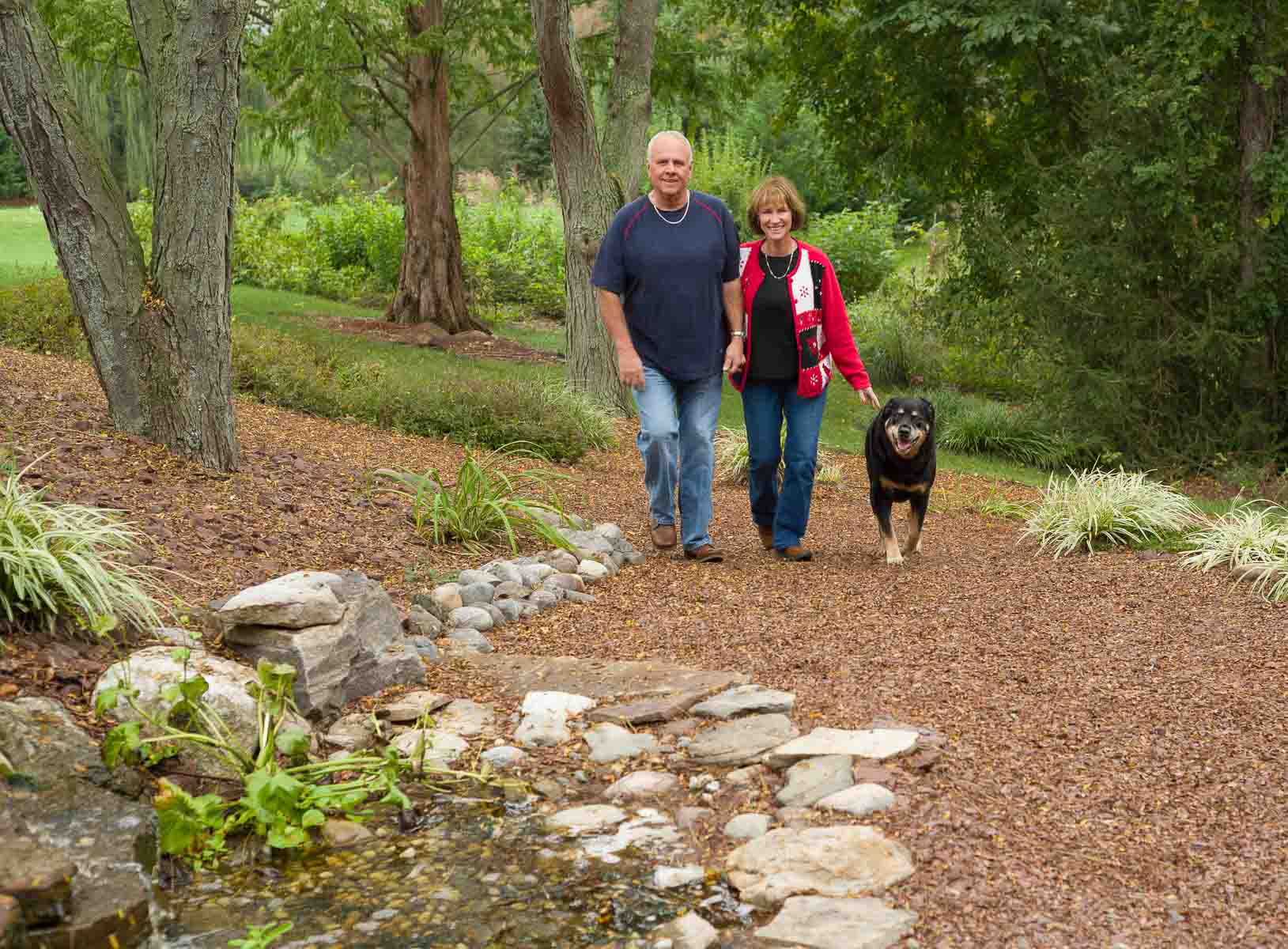 A man and woman walking their dog down the path.