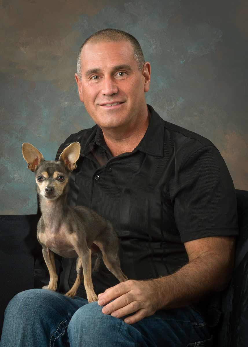 A man sitting on the couch with his dog.