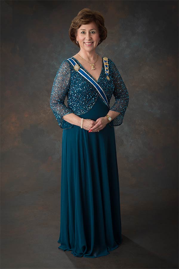 A woman in a blue dress standing on top of a brown floor.