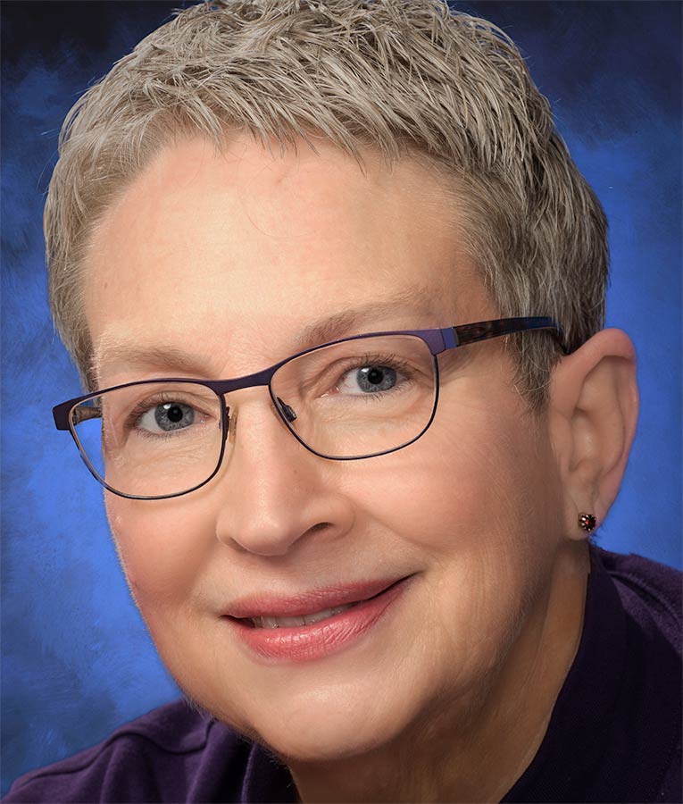 A woman with short hair wearing glasses and smiling.
