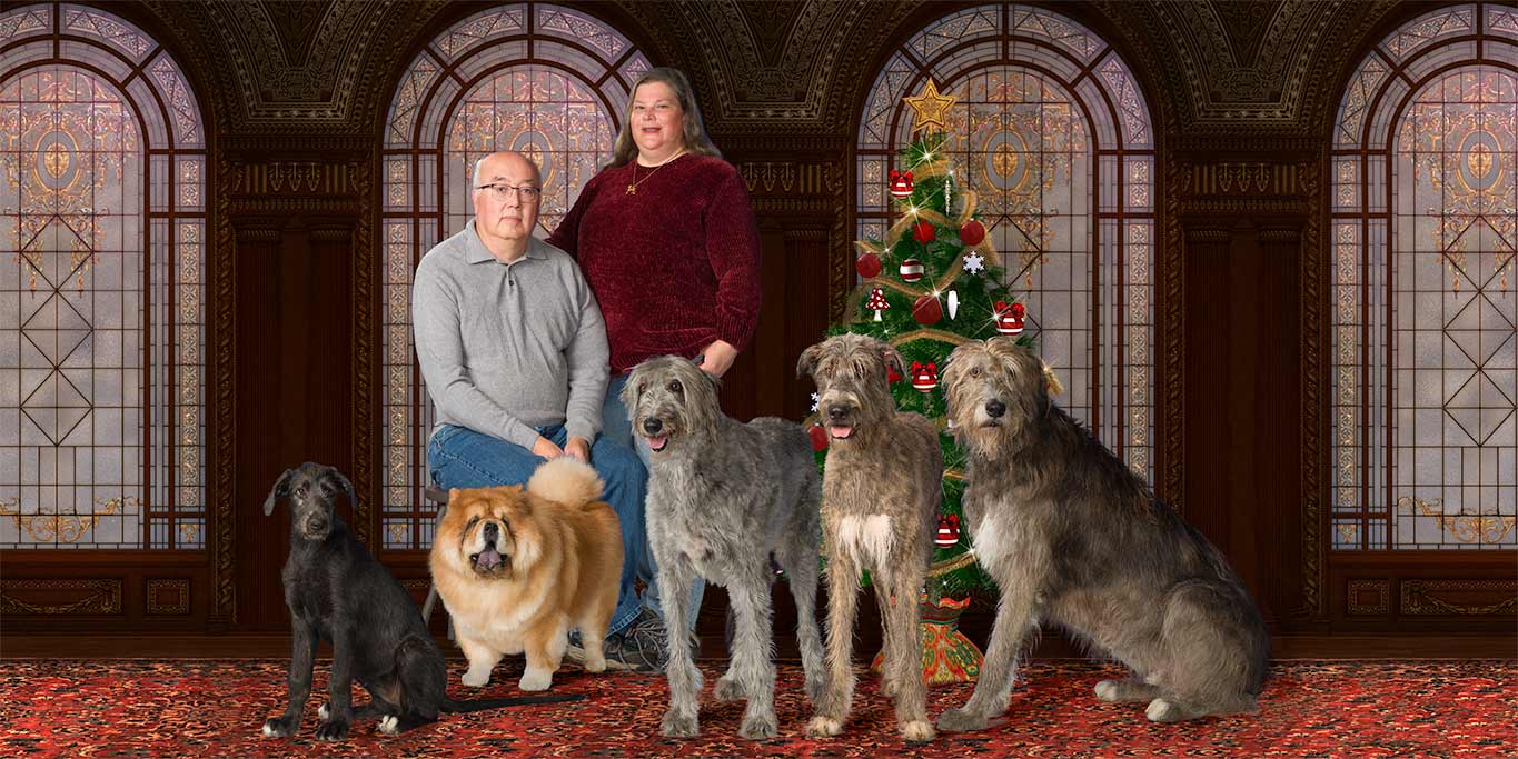 A family with their dogs posing for a christmas picture.