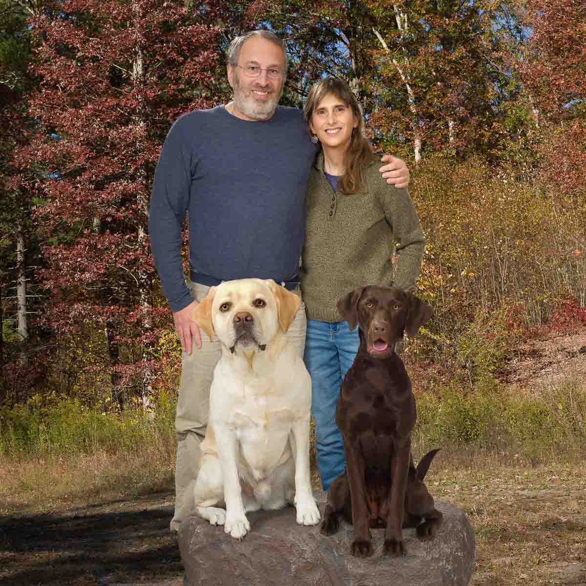 A man and woman standing with two dogs.