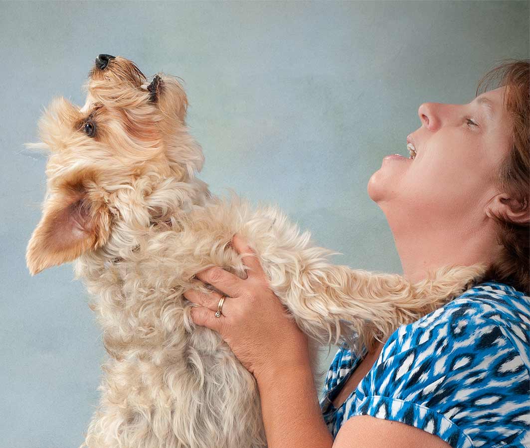 A woman holding onto her dog 's head