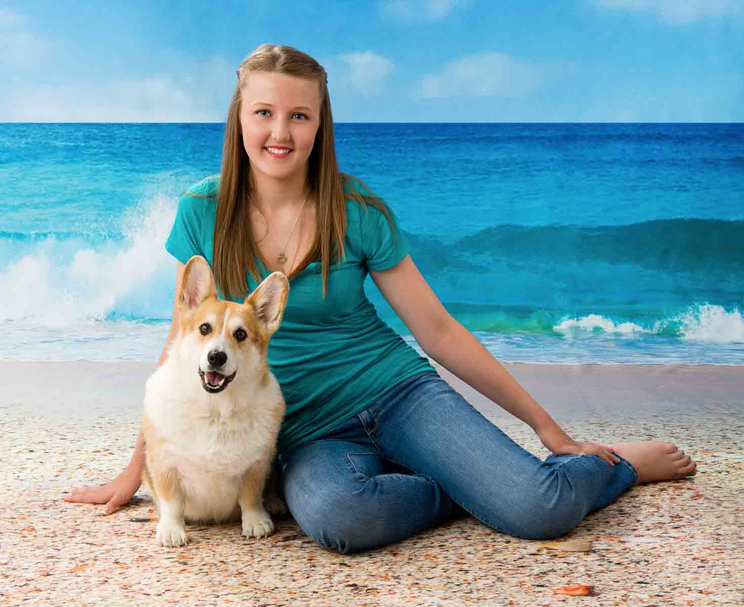 A woman sitting on the beach with her dog.