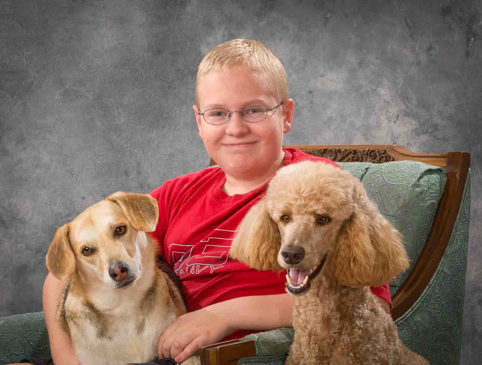 A boy sitting in a chair with two dogs.